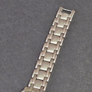 Pu&ograve; includere: Orologio da polso argentato con cinturino a maglie rettangolari. Il quadrante dell'orologio presenta un design di personaggi dei cartoni animati su sfondo marrone chiaro. Display analogico classico.
