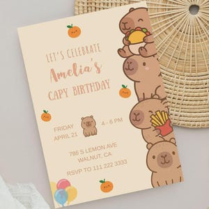Może przedstawiać: Jasnobeżowe zaproszenie urodzinowe z napisem "LET'S CELEBRATE Amelia's CAPY BIRTHDAY". Zaproszenie zawiera ilustracje kapibar i pomarańczy. Uwzględniono r&oacute;wnież datę, godzinę i adres.