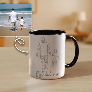 May include: White ceramic mug with a black interior and handle. The mug features a line drawing of a father and child holding hands, with the text "Best dad ever" in a script font. An image of a father and child walking on a beach is in the background.