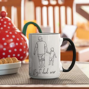 May include: White 15 oz ceramic mug with a black handle and rim. The mug features a line drawing of a parent and child holding hands, with the text "Best dad ever" in a script font.