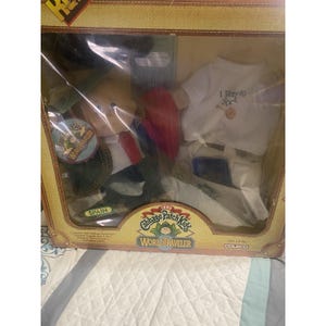 Può includere: Una bambola Cabbage Patch Kids World Traveler del 1985 nella sua scatola originale. La bambola indossa un completo rosso, bianco e blu con un'etichetta Spagna. Include una maglietta bianca con il testo I Went to Spain, una valigia e accessori.