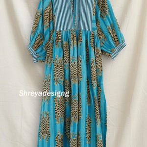 K&ouml;nnte beinhalten: Ein langes, flie&szlig;endes blaues Kleid mit Tigerstreifenmuster. Das Kleid hat ein gestreiftes Oberteil und &Auml;rmel mit einem Schn&uuml;rhalsausschnitt. Der Text "Shreyadesigng" ist auf das Kleid gedruckt.