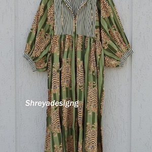 K&ouml;nnte beinhalten: Ein langes, gr&uuml;nes Kleid mit Tigerprint und vertikalen Streifen. Das Kleid hat einen Kragen mit schwarz-wei&szlig;en Streifen, lange &Auml;rmel und den Text "Shreyadesigng".