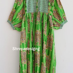 K&ouml;nnte beinhalten: Ein gr&uuml;nes Kleid mit Tigerprint und vertikalen Streifen. Das Kleid hat lange &Auml;rmel und einen runden Ausschnitt mit Streifenmuster. Der Text "Shreyadesigng" ist auf der Vorderseite des Kleides zu sehen.