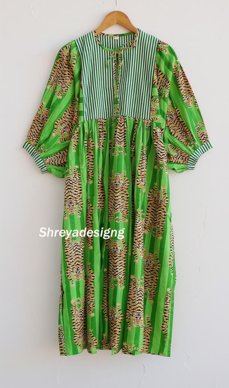 K&ouml;nnte beinhalten: Ein gr&uuml;nes Kleid mit Tigerprint und vertikalen Streifen. Das Kleid hat lange &Auml;rmel und einen runden Ausschnitt mit Streifenmuster. Der Text "Shreyadesigng" ist auf der Vorderseite des Kleides zu sehen.