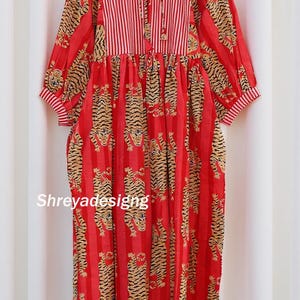 K&ouml;nnte beinhalten: Rotes Kleid mit Tigerprint und vertikalen Streifen. Das Kleid hat lange &Auml;rmel mit gestreiften Manschetten und ein gestreiftes Oberteil mit Bindeband. Der Text "Shreyadesigng" ist auf dem Kleid zu sehen.