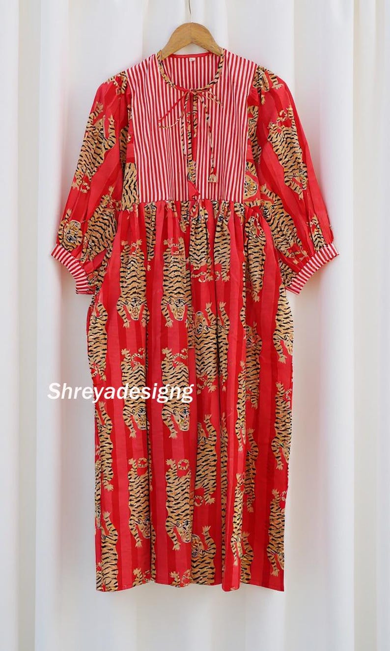 K&ouml;nnte beinhalten: Rotes Kleid mit Tigerprint und vertikalen Streifen. Das Kleid hat lange &Auml;rmel mit gestreiften Manschetten und ein gestreiftes Oberteil mit Bindeband. Der Text "Shreyadesigng" ist auf dem Kleid zu sehen.