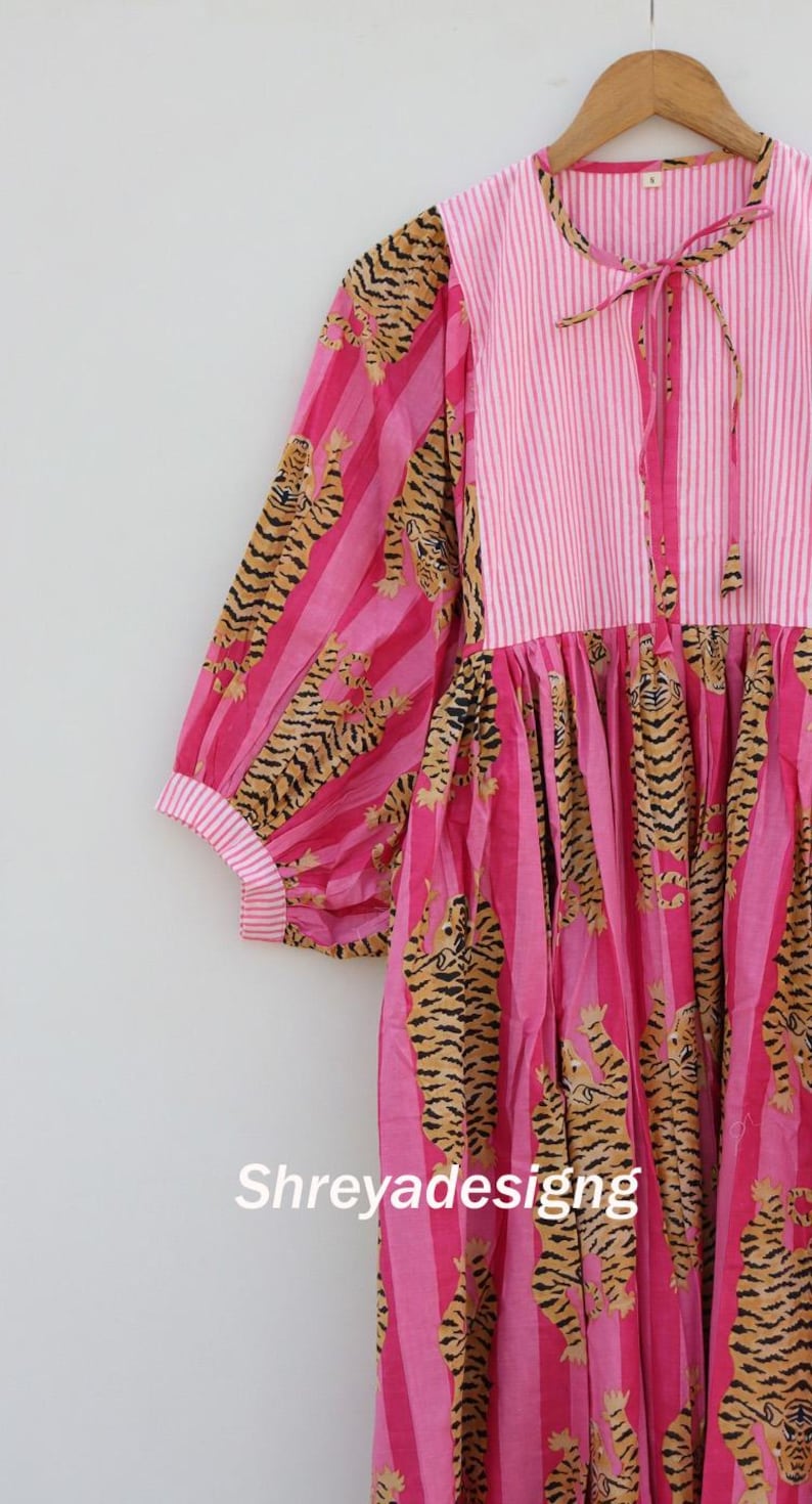 K&ouml;nnte beinhalten: Rosa Kleid mit gestreiftem Oberteil und &Auml;rmeln mit Tigerprint. Das Kleid hat ein Bindeband am Hals und der Text "Shreyadesigng" ist auf der Vorderseite sichtbar.