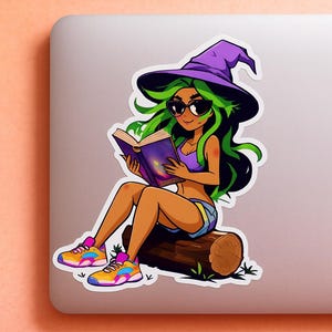 May include: A sticker of a cartoon witch with green hair and sunglasses, wearing a purple witch hat and reading a book. She is sitting on a log and wearing colourful trainers. The sticker is on a laptop.