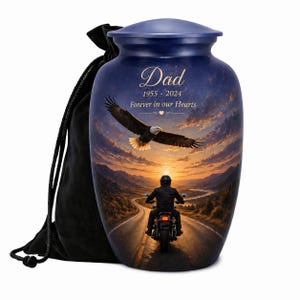 May include: A blue cremation urn with a lid, featuring a sunset scene with an eagle and a motorcyclist. The urn is inscribed with "Dad 1955-2024 Forever in our Hearts." Includes a black drawstring bag.