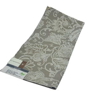 May include: A sample of Kravet fabric featuring a detailed floral pattern in shades of beige and off-white. The fabric has a textured appearance and a label attached with product information.