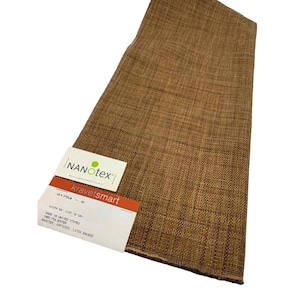 May include: Brown fabric with a woven texture. The fabric has a tag that reads "NANOTEX" and "kravetsmart". The tag also indicates the width is 54 inches. The fabric is made in the United States of 100% polyester.