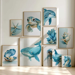 May include: A collection of framed watercolor paintings featuring marine life. The artwork includes a sea turtle, dolphin, whale, seahorse, starfish, coral, and a seashell. The color palette is primarily shades of blue and white, with gold frames.