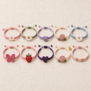 May include: A collection of ten handmade crochet bracelets in various colors. Each bracelet features a different design, including flowers, hearts, a butterfly, and a strawberry. The bracelets are adjustable and have a delicate, feminine aesthetic.