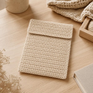 Peut inclure: Une pochette rectangulaire en crochet beige dotée d'un rabat. L'article est réalisé avec un point serré et régulier en fil beige clair neutre, formant une pochette plate de style enveloppe avec une texture uniforme et soignée.
