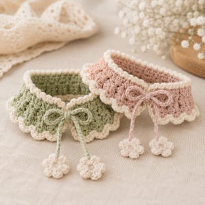 Peut inclure: Deux colliers crochetés, un vert sauge et un rose, avec des bords festonnés blancs et des nœuds. Chaque collier a une paire d'ornements en forme de fleur. Les colliers sont probablement pour animaux de compagnie ou poupées.