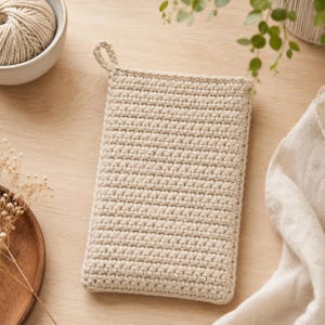 Peut inclure: Une pochette rectangulaire en crochet beige présentant un motif de points dense et uniforme, avec une petite boucle intégrée dans le coin supérieur pour la suspendre. L'objet est fabriqué en fil uni et conserve une forme plate et structurée.