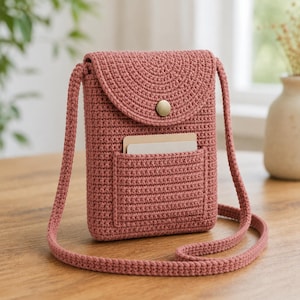 Peut inclure: Un sac à bandoulière en crochet rose poudré avec une fermeture à rabat et une petite poche avant. Le sac est doté d'une longue bandoulière et d'un bouton doré. La poche contient deux cartes. Le sac est fait d'un fil doux et texturé.