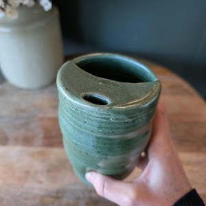 May include: A white ceramic mug with a black handle and the text "But First, Coffee" in a handwritten style. The mug is on a white surface. The mug is 4 inches tall.
