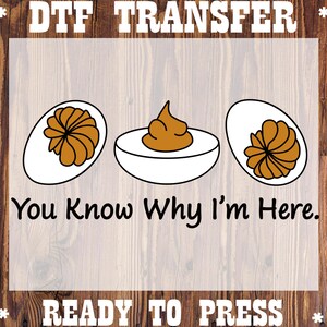 May include: DTF transfer design featuring three deviled eggs with brown filling and the text "You Know Why I'm Here." The words "READY TO PRESS" are also included. The design is on a wood grain background.