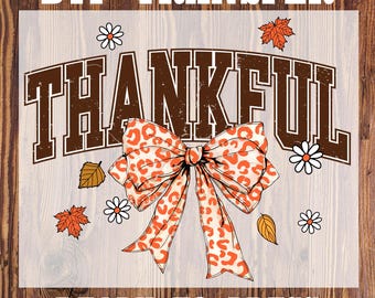 May include: DTF transfer with the word "THANKFUL" in brown, vintage-style lettering. A large orange and white leopard print bow is centered below the word. The design includes fall leaves and daisies. The text "READY TO PRESS" is at the bottom.