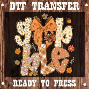 May include: DTF TRANSFER graphic with the words "GIVE THANKS" in a fall-themed design. The letters are decorated with patterns, including floral, plaid, and polka dots. An orange bow and a turkey wearing a hat are also featured. The text "READY TO PRESS" is at the bottom.
