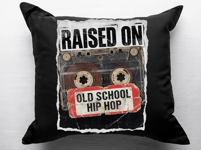 May include: Black square throw pillow featuring a vintage cassette tape design. The tape image has the words "RAISED ON" above and "OLD SCHOOL HIP HOP" below. The pillow is a decorative item.