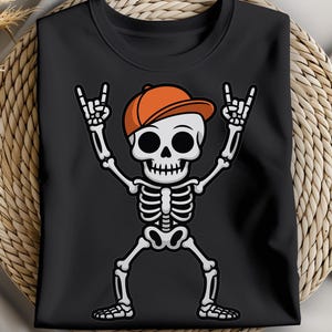 May include: Black t-shirt featuring a cartoon skeleton wearing an orange baseball cap and making a rock and roll hand gesture. The skeleton has a white skull and bones. The design is centered on the shirt.