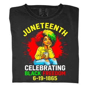 May include: Black t-shirt with a graphic celebrating Juneteenth. The design features a woman with colorful hair, a yellow shirt, and blue jeans, holding a drink. Text includes "Juneteenth" and "Celebrating Black Freedom 6-19-1865."