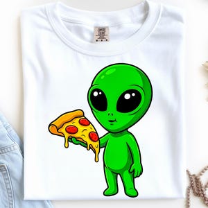 Może przedstawiać: Biała koszulka z kreskówkowym zielonym kosmitą trzymającym kawałek pizzy. Kosmita ma duże czarne oczy i się uśmiecha. Pizza ma żółtą skórkę i czerwone pepperoni. Koszulka ma okrągły dekolt i krótkie rękawy.