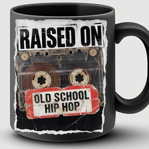 May include: Black ceramic mug featuring a cassette tape design with the words "RAISED ON" above the tape and "OLD SCHOOL HIP HOP" below. The mug has a black handle and a glossy finish.