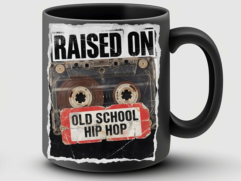 May include: Black ceramic mug featuring a cassette tape design with the words "RAISED ON" above the tape and "OLD SCHOOL HIP HOP" below. The mug has a black handle and a glossy finish.