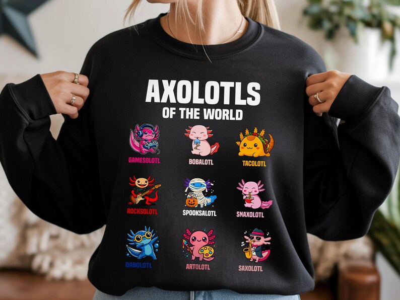 May include: Black sweatshirt with the text "AXOLOTLS OF THE WORLD" in white. Below the text are nine colorful axolotl illustrations, each with a unique theme, including a gamer, a taco, and a rockstar.