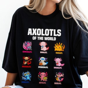 May include: Black t-shirt featuring the text "AXOLOTLS OF THE WORLD" above nine colorful axolotl illustrations. Each axolotl is uniquely designed, with names like "Gamesolotl" and "Tacolotl" below them. The shirt is a casual, fun design.
