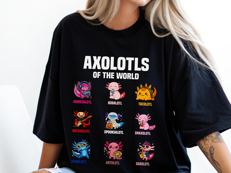 May include: Black t-shirt featuring the text "AXOLOTLS OF THE WORLD" above nine colorful axolotl illustrations. Each axolotl is uniquely designed, with names like "Gamesolotl" and "Tacolotl" below them. The shirt is a casual, fun design.