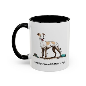 May include: A white ceramic mug with a black handle and interior rim. The mug features a graphic of a muddy white and tan dog standing near a grooming brush and a bottle, with the text "Freshly Groomed (5 Minutes Ago)" printed below.