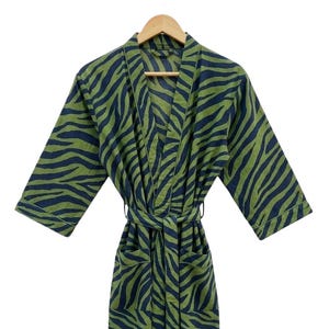 May include: A white ceramic mug with a black handle and the text "But First, Coffee" in a bold, black font. The mug is set against a blurred background, suggesting a cozy setting.
