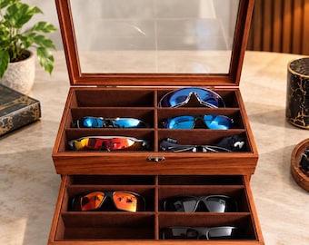 May include: A wooden eyewear storage box with a clear glass lid and a pull-out drawer. The interior is lined with brown fabric and features eight individual compartments, each containing a pair of sunglasses with various colored lenses.