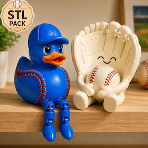 Könnte beinhalten: Eine blaue Gummiente mit blauer Baseballkappe und roten Nahtdetails am Körper, neben einer cremefarbenen Baseballhandschuh-Figur, die einen Baseball mit lächelndem Gesicht hält, beide mit beweglichen Beinen zum Sitzen auf einer Kante.