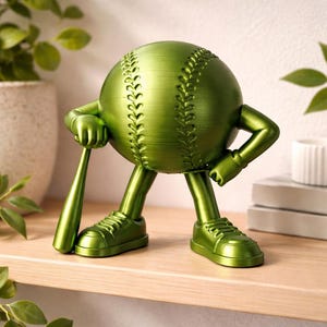 Puede incluir: Una figura verde con forma de pelota de béisbol con brazos, piernas y zapatillas deportivas. La figura sostiene un bate de béisbol y tiene costuras detalladas en la pelota. Está sobre una estantería de madera.