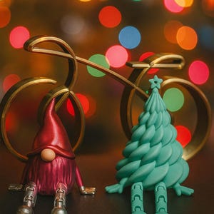 K&ouml;nnte beinhalten: Eine skurrile Weihnachtsszene mit einem roten Zwerg und einer t&uuml;rkisfarbenen Weihnachtsbaumfigur. Im Hintergrund befindet sich ein goldener Fahrradschmuck mit bunten Bokeh-Lichtern. Der Zwerg hat silberfarbene F&uuml;&szlig;e, und der Baum hat einen Stern oben drauf.