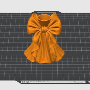 Puede incluir: Un jarr&oacute;n decorativo naranja con un dise&ntilde;o de lazo grande. El jarr&oacute;n tiene una abertura cil&iacute;ndrica en la parte superior y una base con volantes en forma de falda. El lazo est&aacute; centrado y a&ntilde;ade un toque de elegancia.