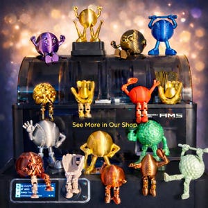 May include: A collection of colorful, 3D-printed sports-themed figurines, including baseballs, golf balls, and tennis balls with articulated limbs. The text "See More in Our Shop" is visible. The figurines are displayed on a black machine.