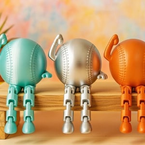 May include: Three baseball-themed figurines in teal, silver, and orange, each with articulated legs and arms. They are seated on a wooden surface, with a colorful background. The baseballs have stitched details.