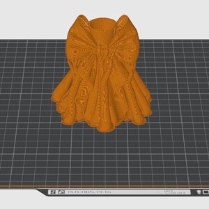 Puede incluir: Un lazo naranja impreso en 3D, con texturas y pliegues detallados, se encuentra sobre una superficie de cuadr&iacute;cula gris. El dise&ntilde;o del lazo es intrincado, con una apariencia en capas. El fondo incluye el texto "Bambu Textured PE Plate".