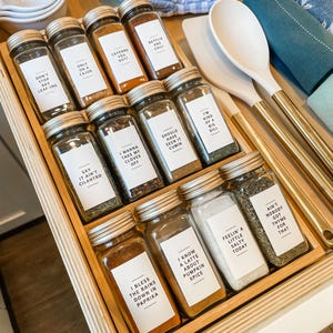 May include: A wooden drawer organizer with glass spice jars labeled with funny sayings. The labels include "Don't Stop Bay Leaf-ing", "Only on a Cajun", "Cayenne You Nott", "Netflix and Chile", "Say It Ain't Cilantro", "I Wanna Take My Cloves Off", "Should Have Seen It Cumin", "I'm Kind of a Big Dill", "I Bless the Rains Down in Paprika", "I Know a Latte About Pumpkin Spice", "Feelin' a Little Salty Today", "Ain't Nobody Got Thyme for That".