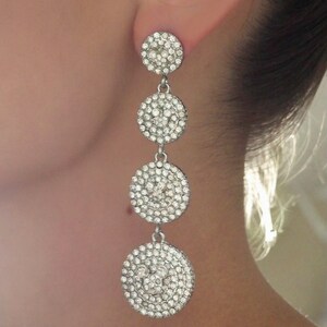 May include: Silver dangle earrings with multiple round crystal-encrusted charms.