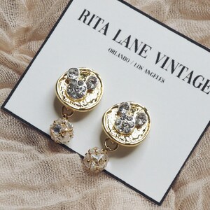 May include: Gold tone earrings with a Mickey Mouse design and clear rhinestones. The earrings have a dangling ball of clear rhinestones.