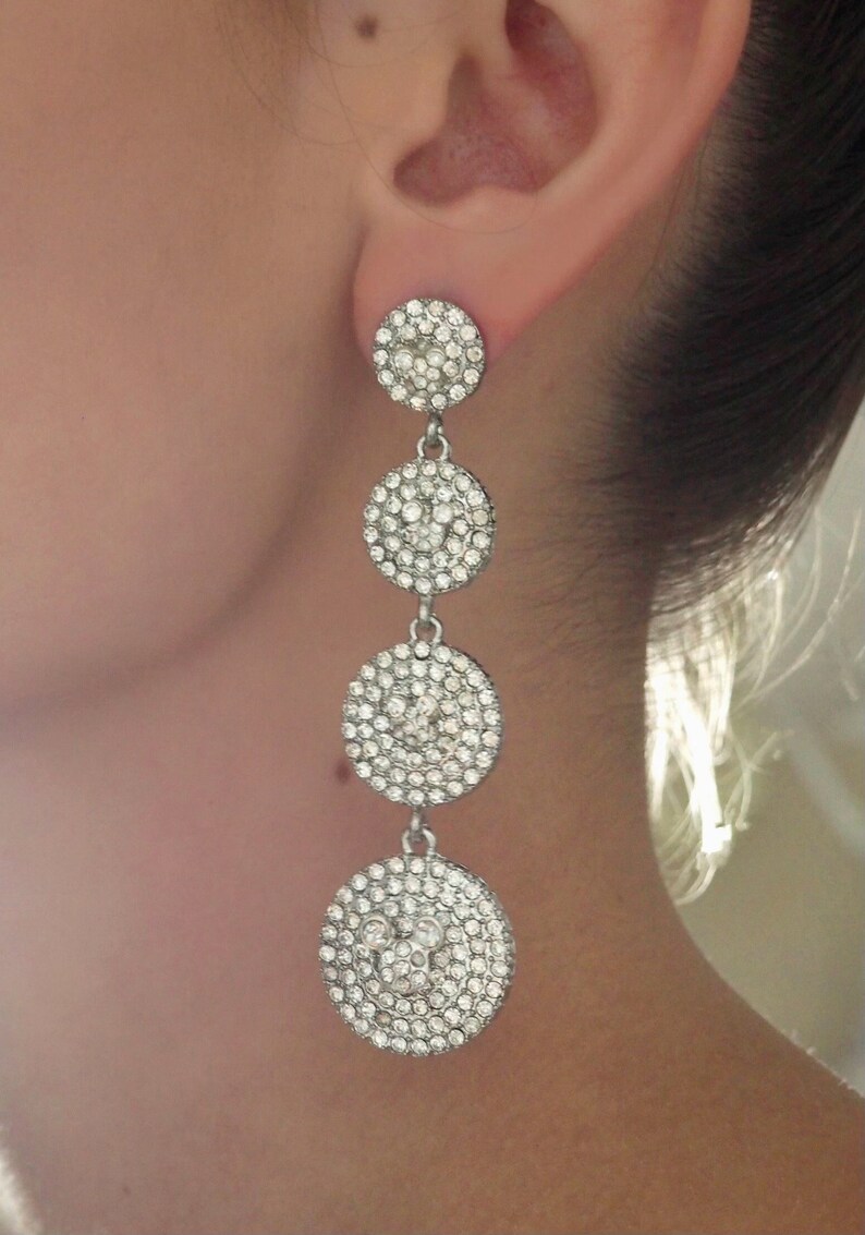 May include: Silver dangle earrings with multiple round crystal-encrusted charms.