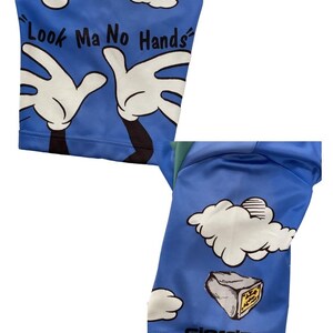 May include: Blue cycling shorts with a cartoon design of hands reaching up to a cloud with the text "Look Ma No Hands". The shorts have a white cloud and a gray rock with the word "Giordana" printed on the bottom.